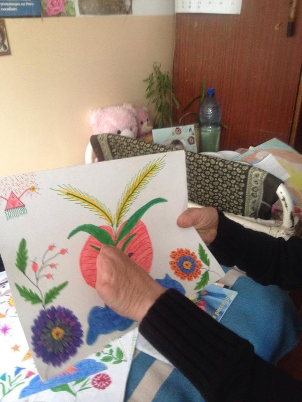 A resident of a home for older people holding her drawings